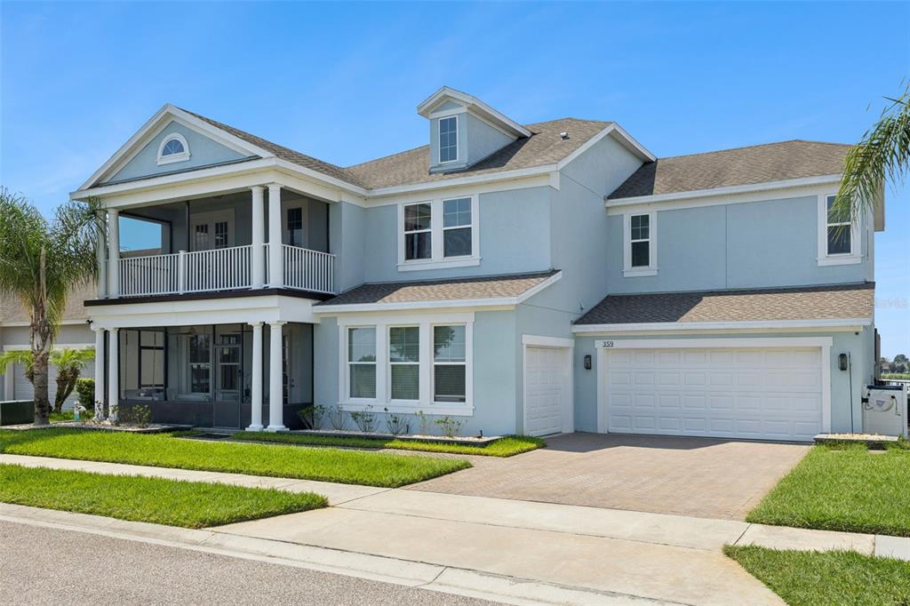 A two-story light blue house with a screened-in porch, balcony, and attached two-car garage — 359 BLUE CYPRESS DRIVE, GROVELAND, FL