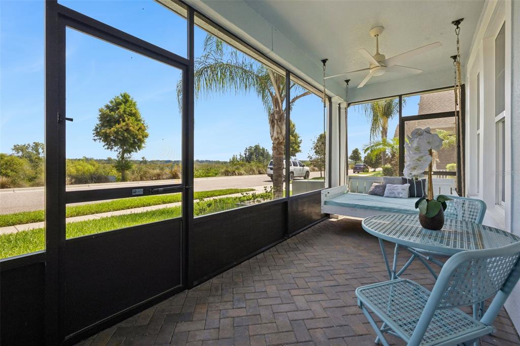 A screened-in porch features a hanging daybed, a metal bistro set, and paver flooring — 359 BLUE CYPRESS DRIVE, GROVELAND, FL