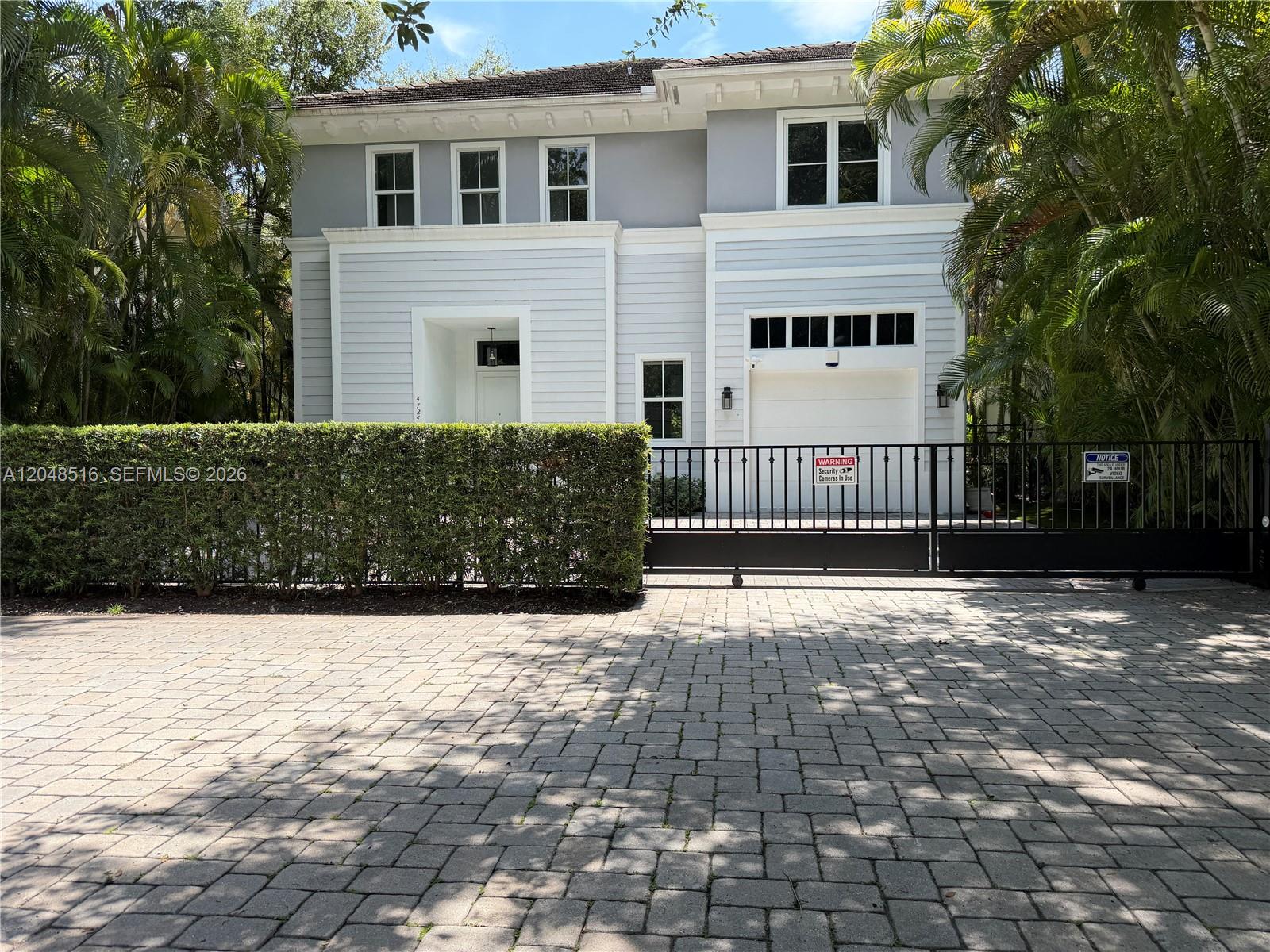 A two-story house with light siding, a gated driveway, and a hedge-lined front yard — 4724 SW 72nd ST, Miami FL 33143, MIAMI, FL