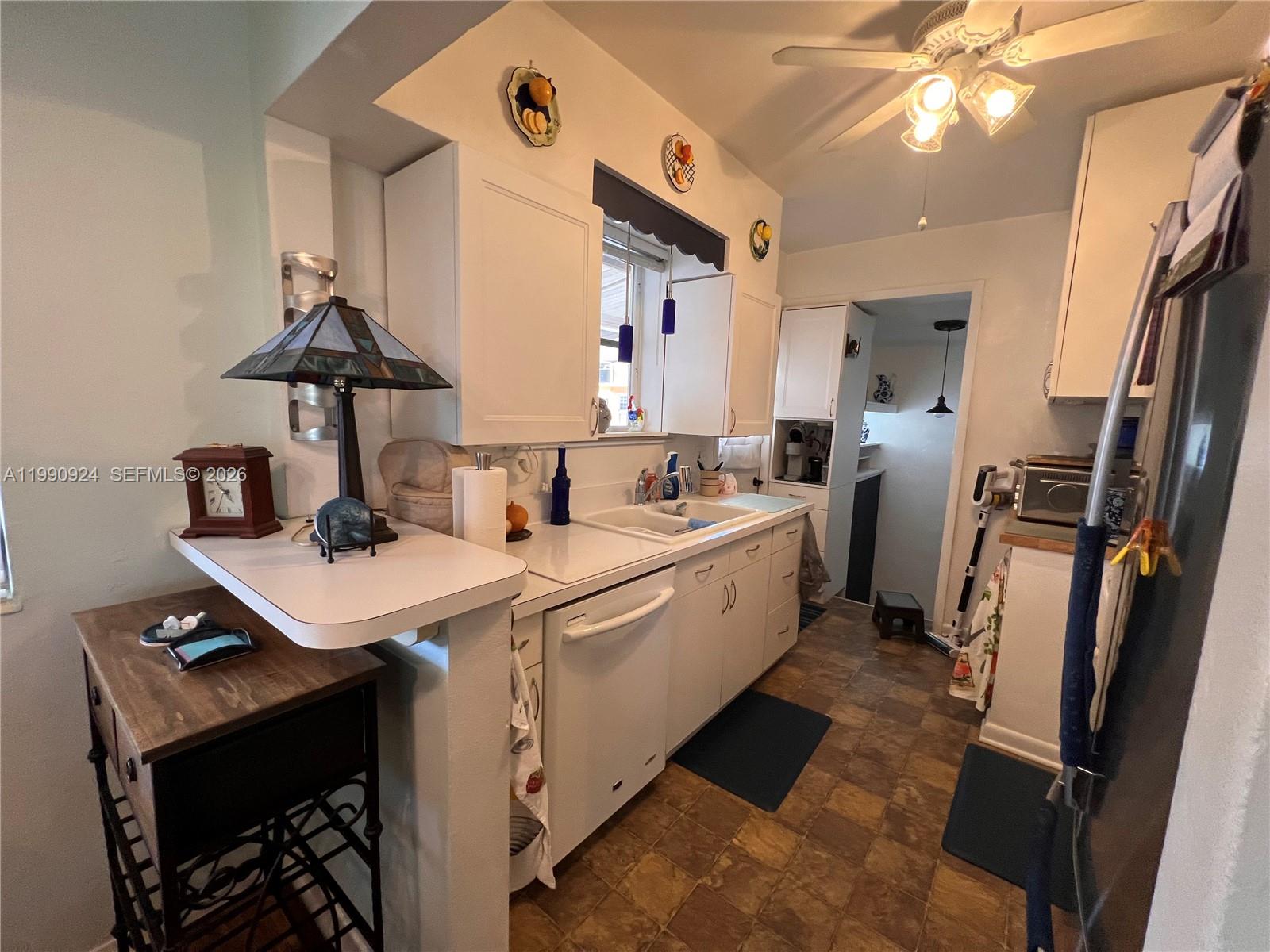 A kitchen features white cabinets, a double sink, a dishwasher, and a ceiling fan — 151 W 63rd St, Hialeah FL 33012, HIALEAH, FL