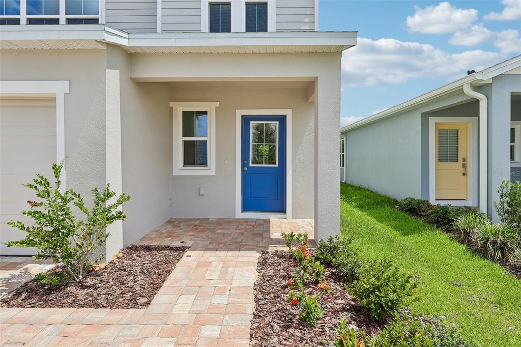 A front exterior view of a house with a blue door and a brick walkway — 1357 JUNE LAKE LOOP, HAINES CITY, FL