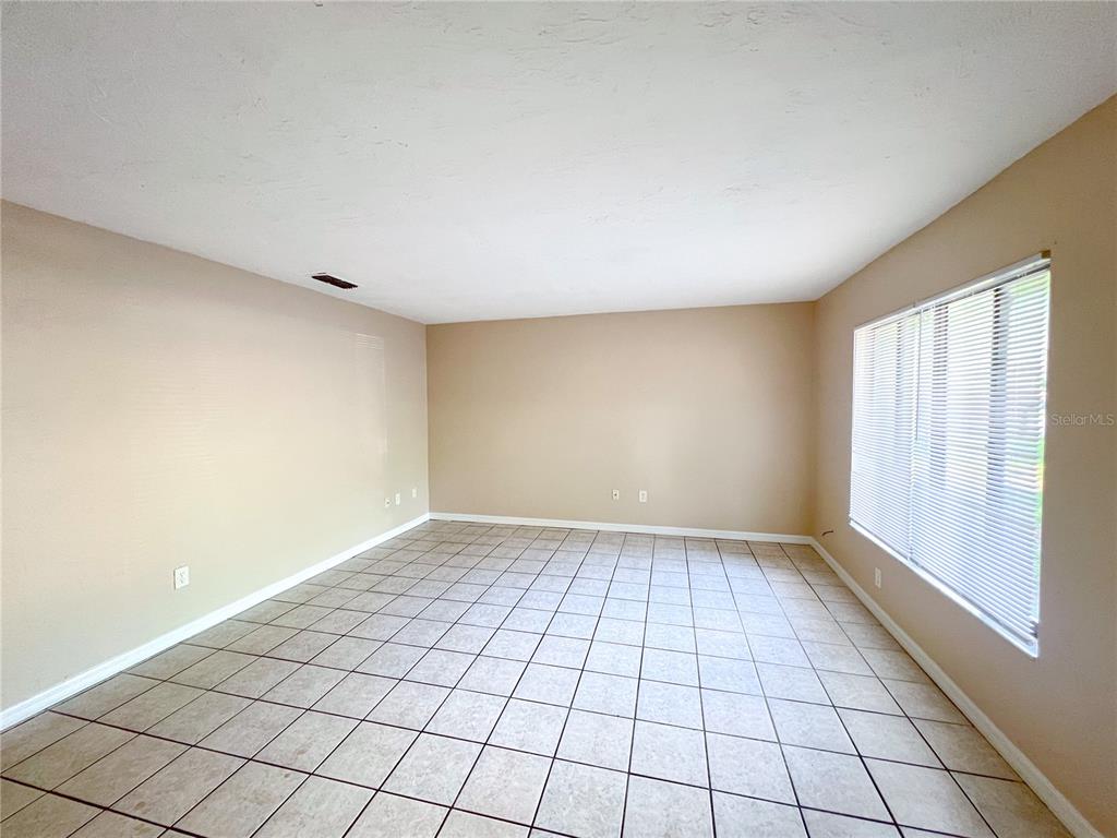 An empty room features beige walls, a white ceiling, and light-colored square floor tiles — 703 SW 69TH TERRACE UNIT B, GAINESVILLE, FL