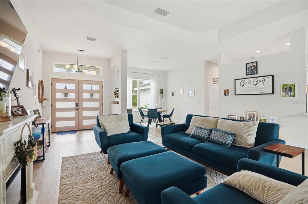 A bright living room features blue furniture, a fireplace, and a double-door entryway — 7279 BLACKBIRD AVENUE, WEEKI WACHEE, FL