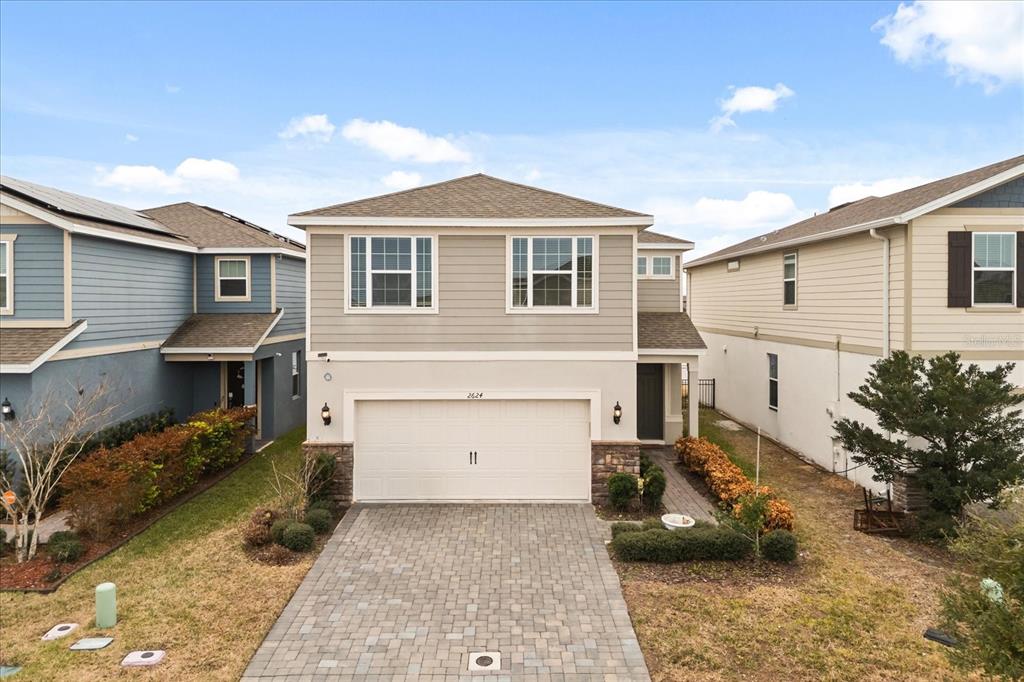 A two-story house with a beige stucco and siding exterior and a paved driveway — 2624 BLOWING BREEZE AVENUE, KISSIMMEE, FL