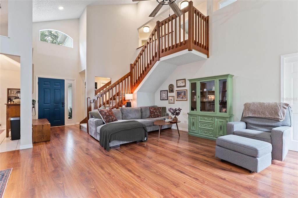 A living room features wood flooring, a staircase with wooden railings, and a green hutch — 3274 MONTROSE CIRCLE, PALM HARBOR, FL