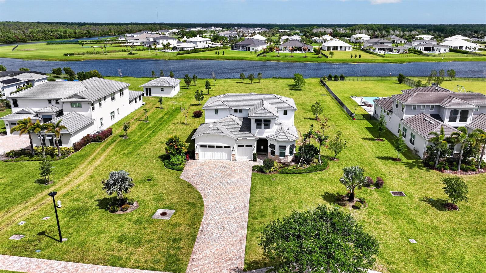 An aerial view shows a two-story house with a brick driveway and a large lawn — 20160 SE Bridgewater Drive, Jupiter FL 33458, JUPITER, FL