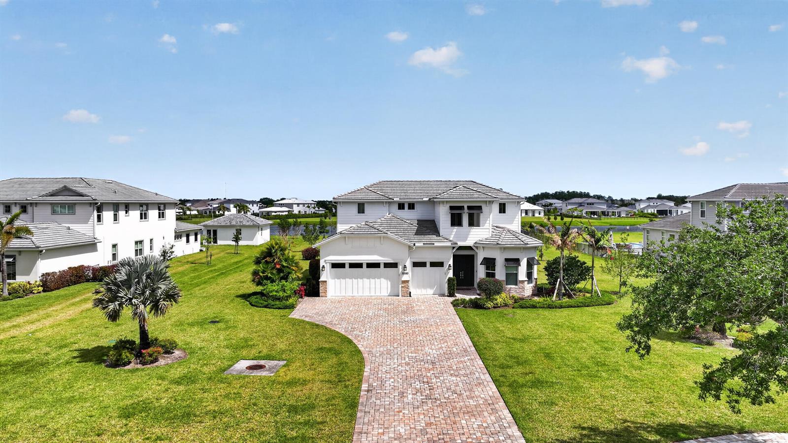 An aerial view of a two-story suburban house with a brick driveway and green lawn — 20160 SE Bridgewater Drive, Jupiter FL 33458, JUPITER, FL