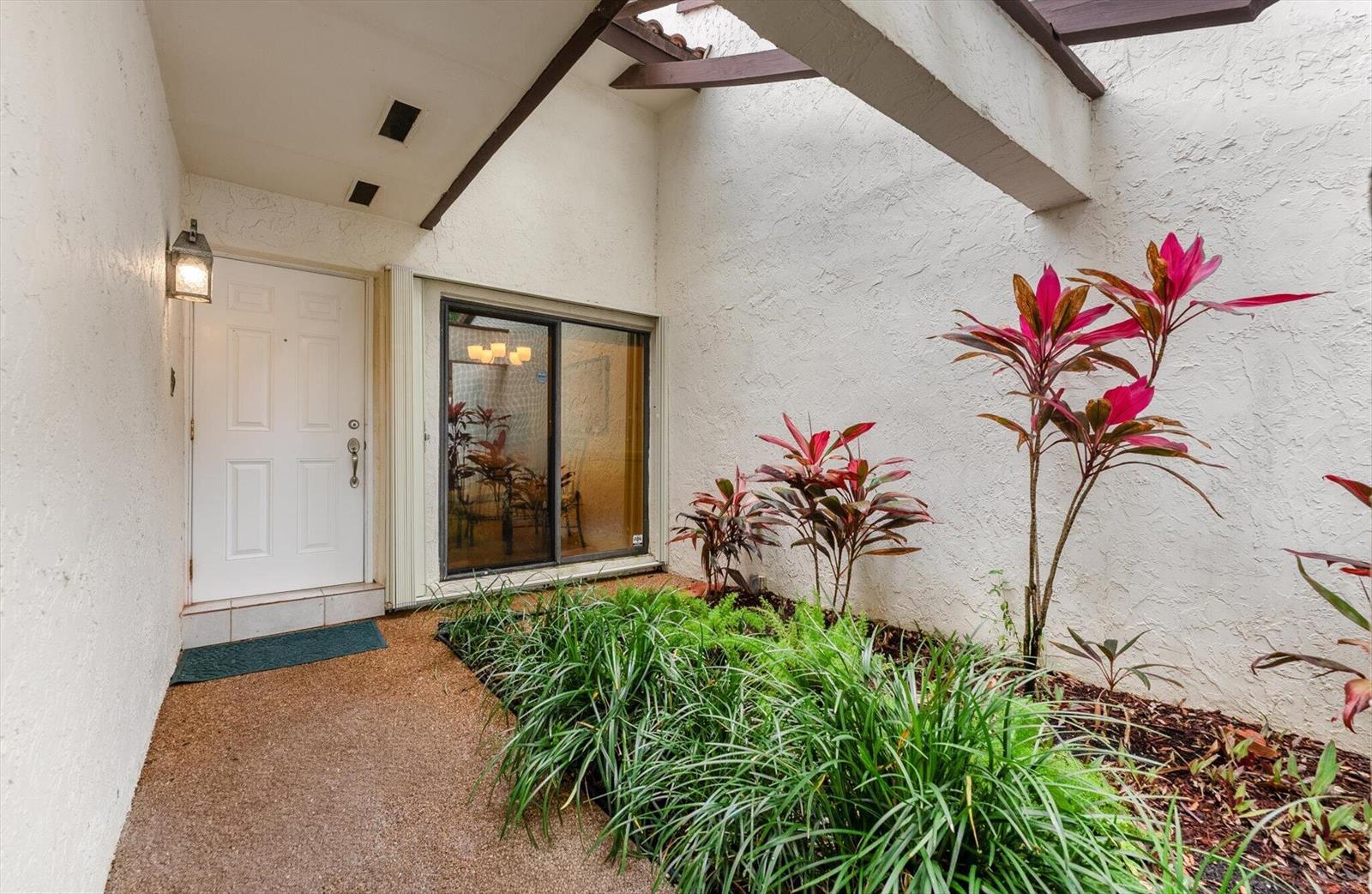 An outdoor entryway features a white door, a sliding glass window, and a garden bed — 6886 Tiburon Circle, Boca Raton FL 33433, BOCA RATON, FL