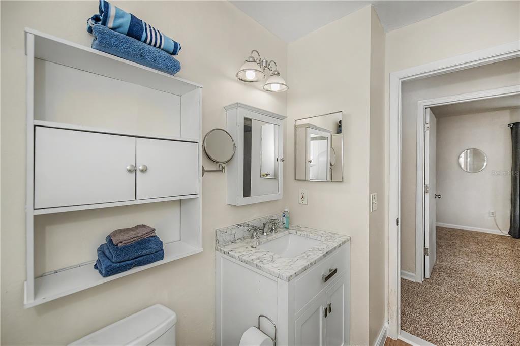 A bedroom features a red bedspread, white walls, carpeted flooring, and two sets of closet doors — 14415 WORTHWHILE ROAD, PORT CHARLOTTE, FL