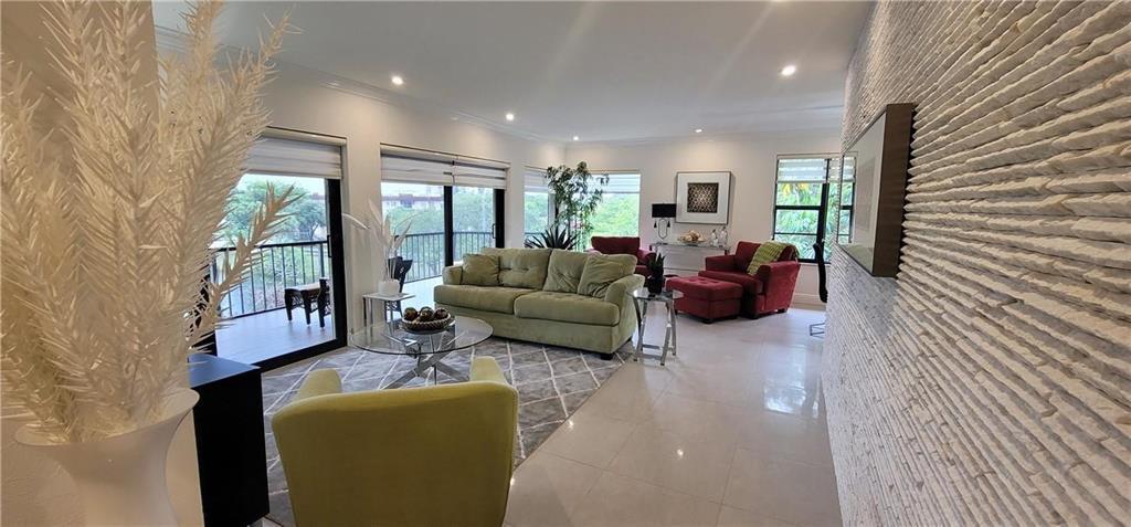 A living room features a textured stone wall, light tile flooring, and a green sofa — 6010 S Falls Circle Drive # 423, Lauderhill FL 33319, LAUDERHILL, FL
