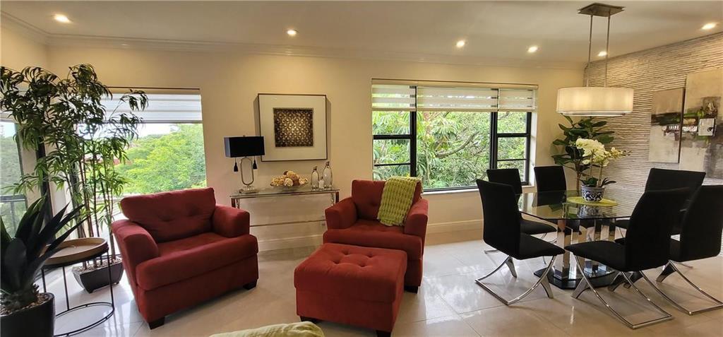 A living and dining area features red armchairs, a glass dining table, and large windows — 6010 S Falls Circle Drive # 423, Lauderhill FL 33319, LAUDERHILL, FL