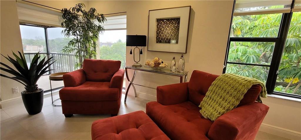 A living room features two red armchairs, a glass console table, and large windows — 6010 S Falls Circle Drive # 423, Lauderhill FL 33319, LAUDERHILL, FL