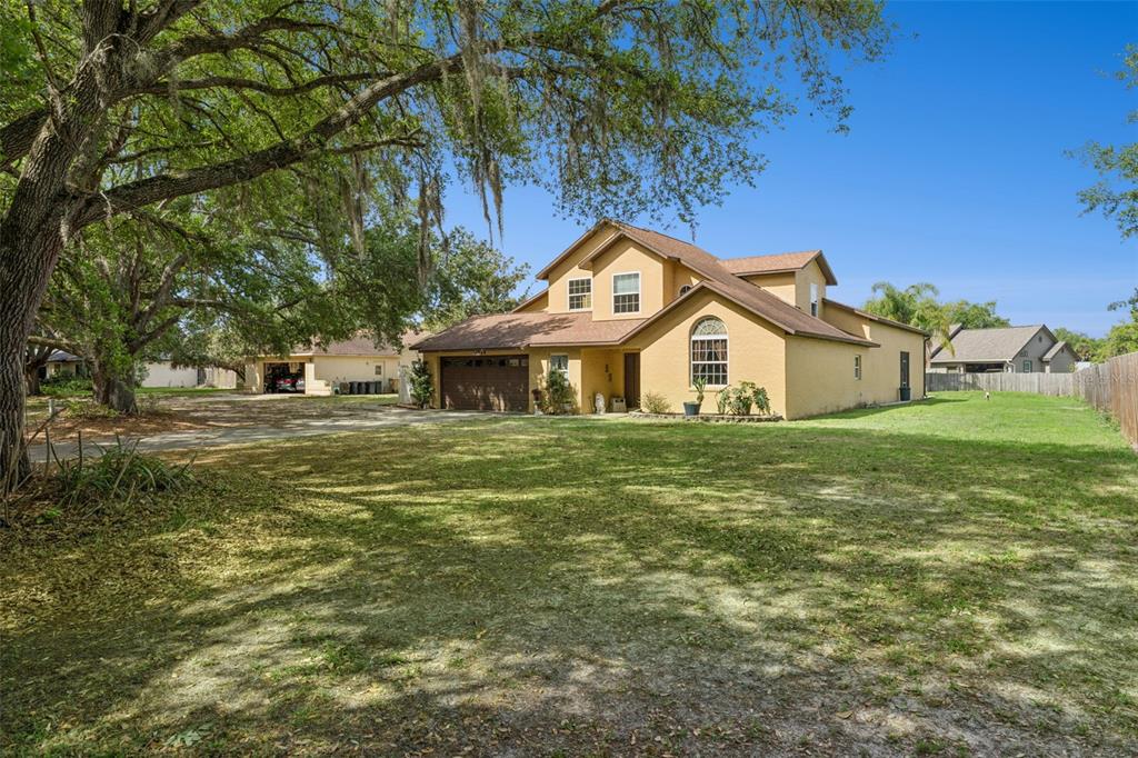 A two-story yellow house with a brown roof, garage, and large front yard — 1714 CHERYL LANE, KISSIMMEE, FL