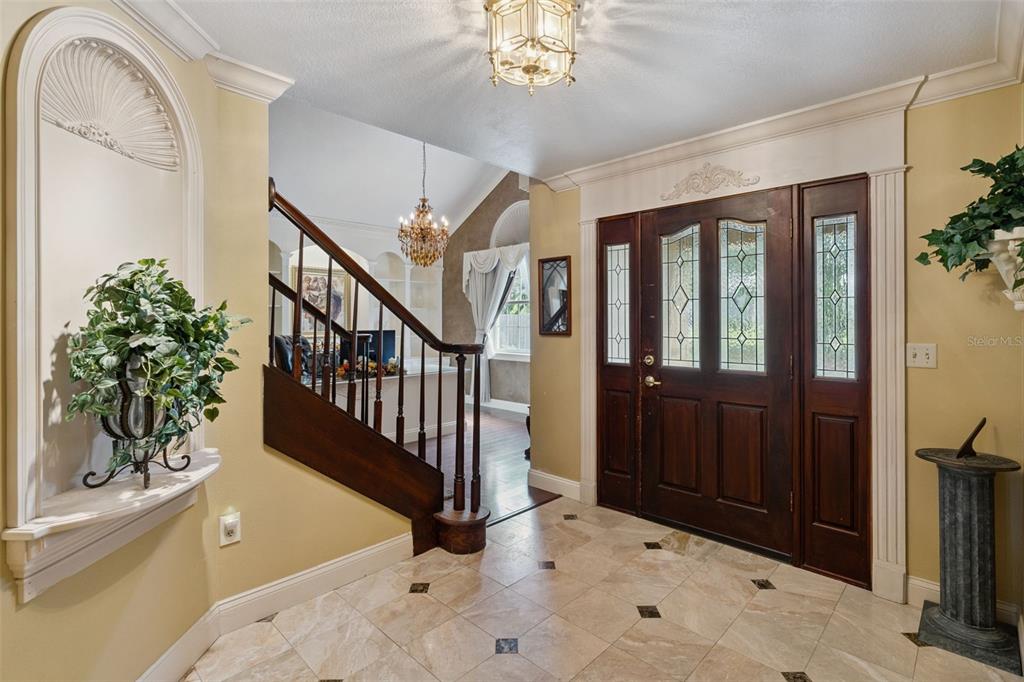 An entryway features a tiled floor, a wooden staircase, and a decorative arched wall niche — 1714 CHERYL LANE, KISSIMMEE, FL