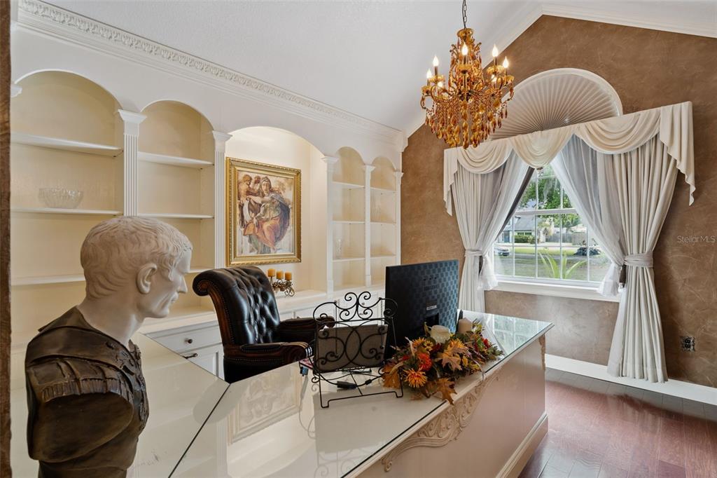 A home office features a glass-topped desk, built-in shelving, a chandelier, and a bust statue — 1714 CHERYL LANE, KISSIMMEE, FL