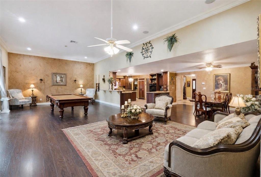 A spacious open-concept living area features a pool table, dining set, and dark wood floors — 1714 CHERYL LANE, KISSIMMEE, FL