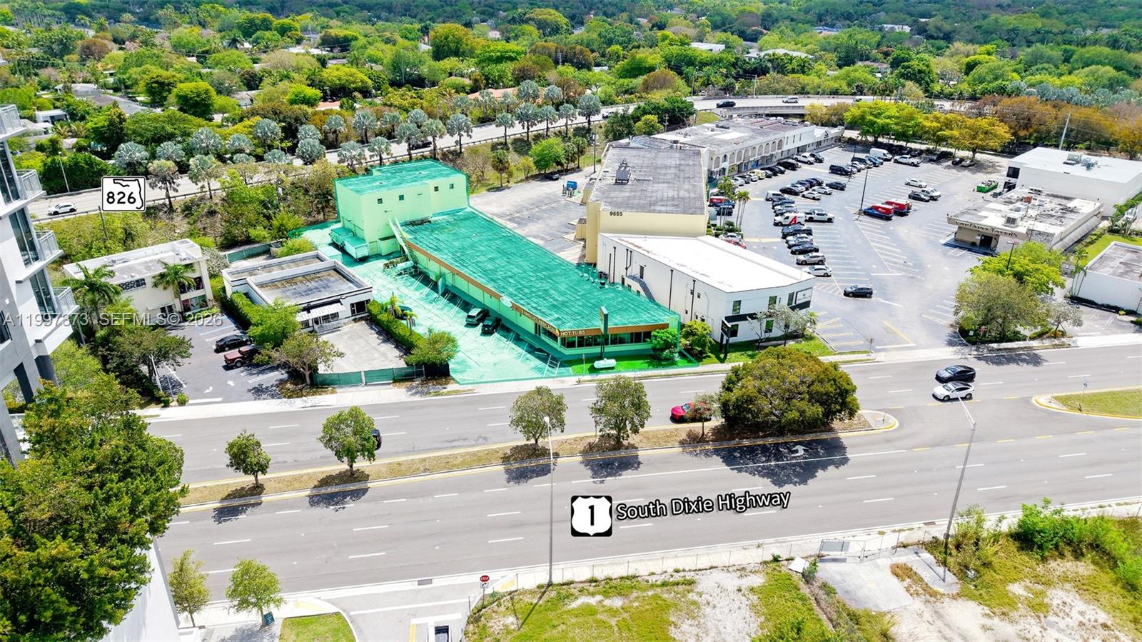 An aerial view shows a commercial building with a green roof next to a parking lot — 9621 S Dixie Hwy, Pinecrest FL 33156, PINECREST, FL