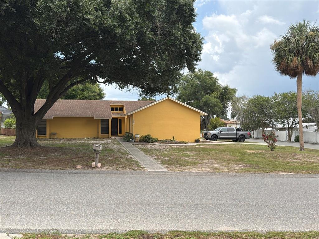 A yellow single-story house with a large oak tree and a pickup truck parked nearby — 7023 FOX CHASE DRIVE, LAKELAND, FL