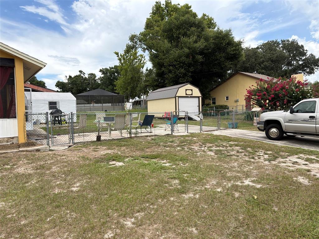 A backyard features a patio with chairs, a shed, a chain-link fence, and a truck — 7023 FOX CHASE DRIVE, LAKELAND, FL