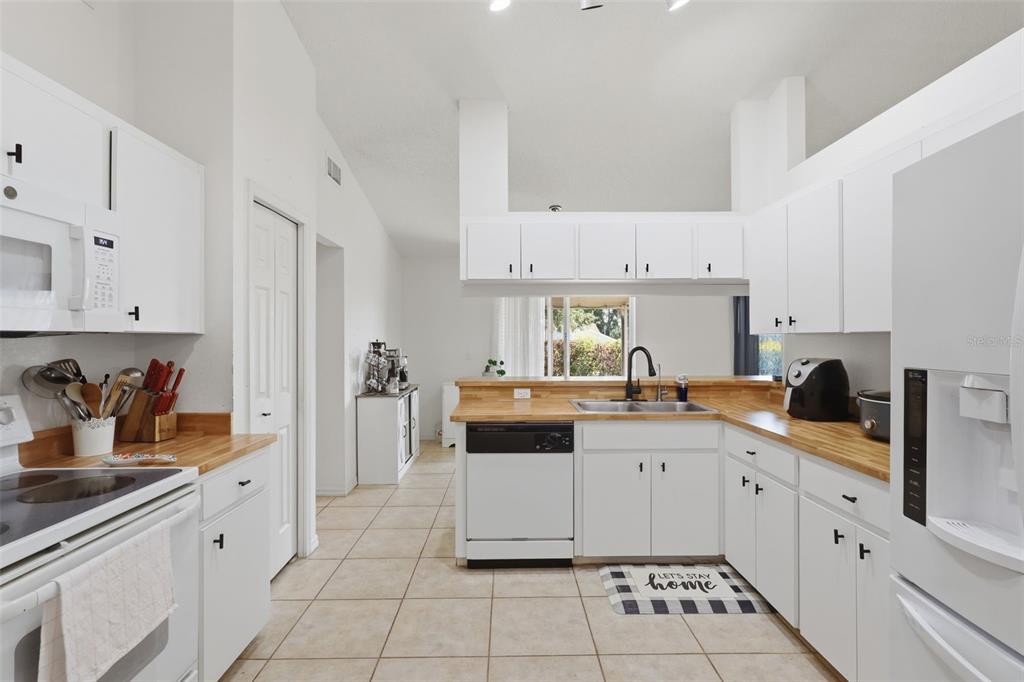 A kitchen features white cabinets, light wood countertops, a dishwasher, and tile flooring — 774 BARCLAY TERRACE, LAKE WALES, FL