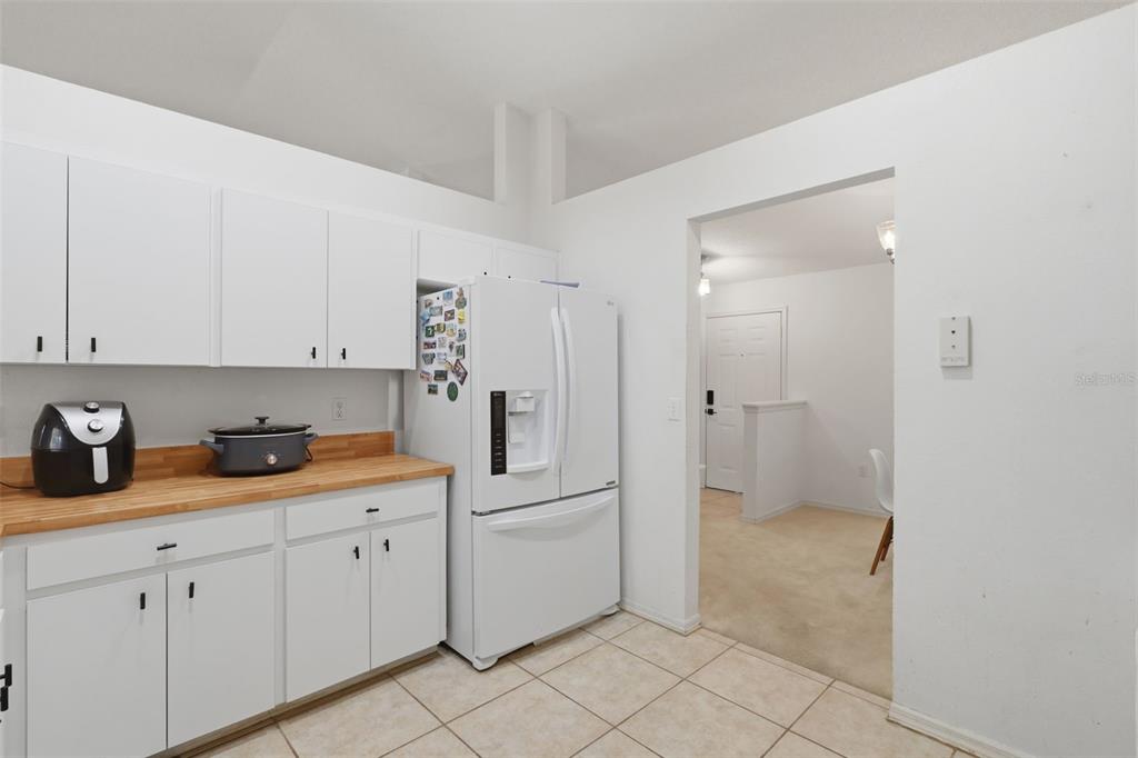 A kitchen with white cabinets, a wood countertop, and a white refrigerator — 774 BARCLAY TERRACE, LAKE WALES, FL