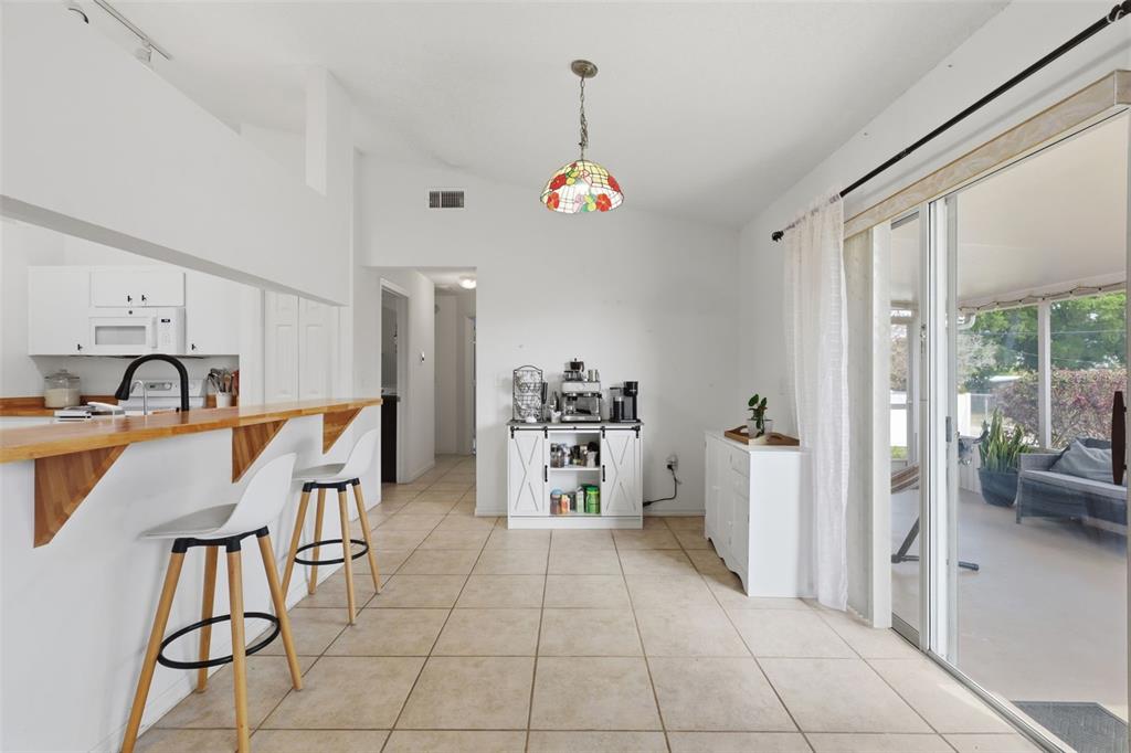 A kitchen with a breakfast bar, tile flooring, and a sliding door to a patio — 774 BARCLAY TERRACE, LAKE WALES, FL