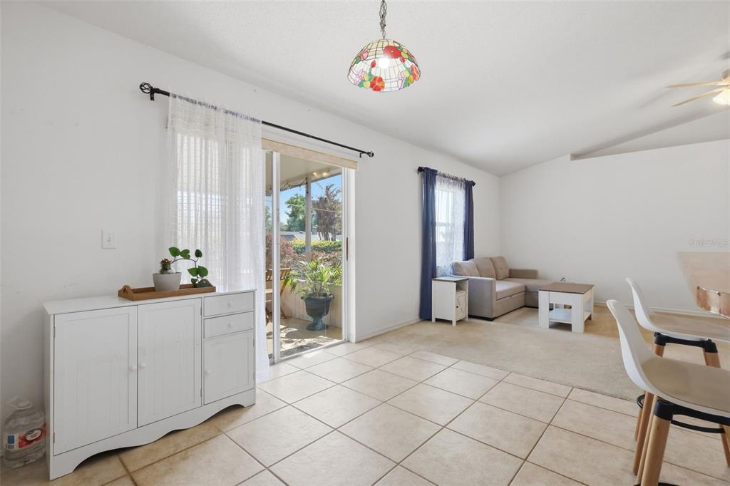 A dining area with tile floors leads to a living room with carpet and sliding doors — 774 BARCLAY TERRACE, LAKE WALES, FL