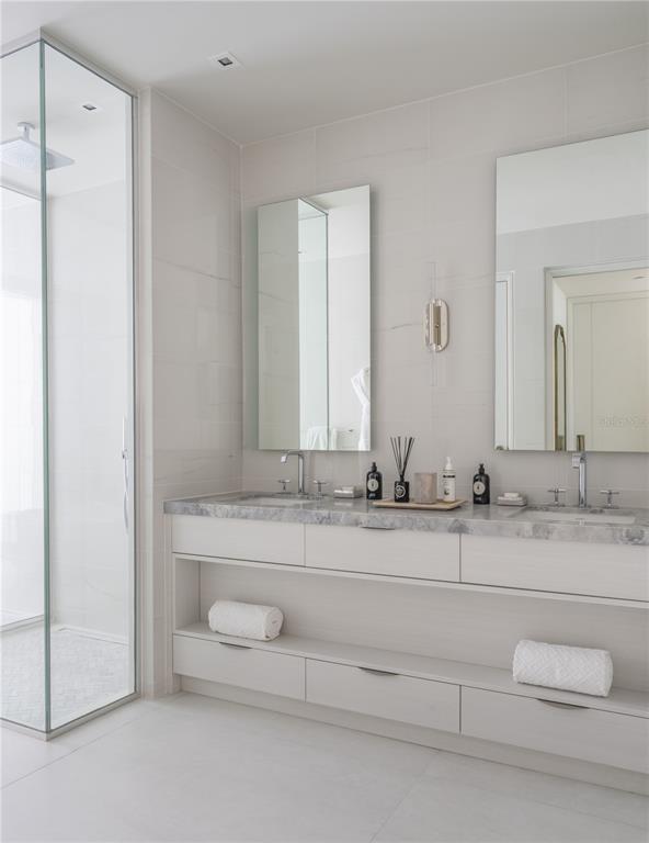 A modern bathroom features a double vanity with a marble countertop and glass shower enclosure — Ocean Drive FOUR SEASONS PRIVATE RESIDENCES UNIT 6401, RIO GRANDE, PR