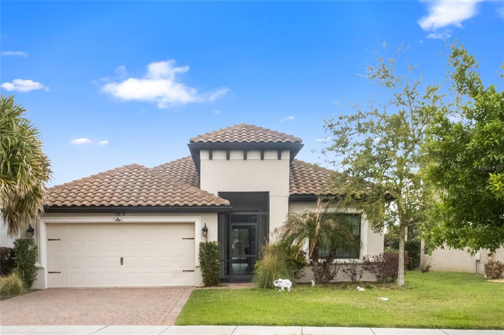 A single-story house with a tiled roof, a two-car garage, and a screened front entryway — 3958 CARRICK BEND DRIVE, KISSIMMEE, FL