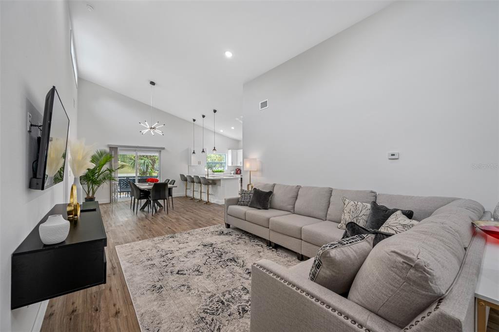 A living room with a gray sectional sofa, a dining area, and an open kitchen — 3717 E CLIFTON STREET, TAMPA, FL