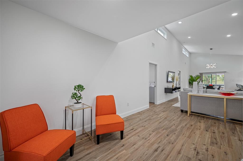 A living area features orange chairs, wood-look flooring, and a vaulted ceiling with recessed lighting — 3717 E CLIFTON STREET, TAMPA, FL