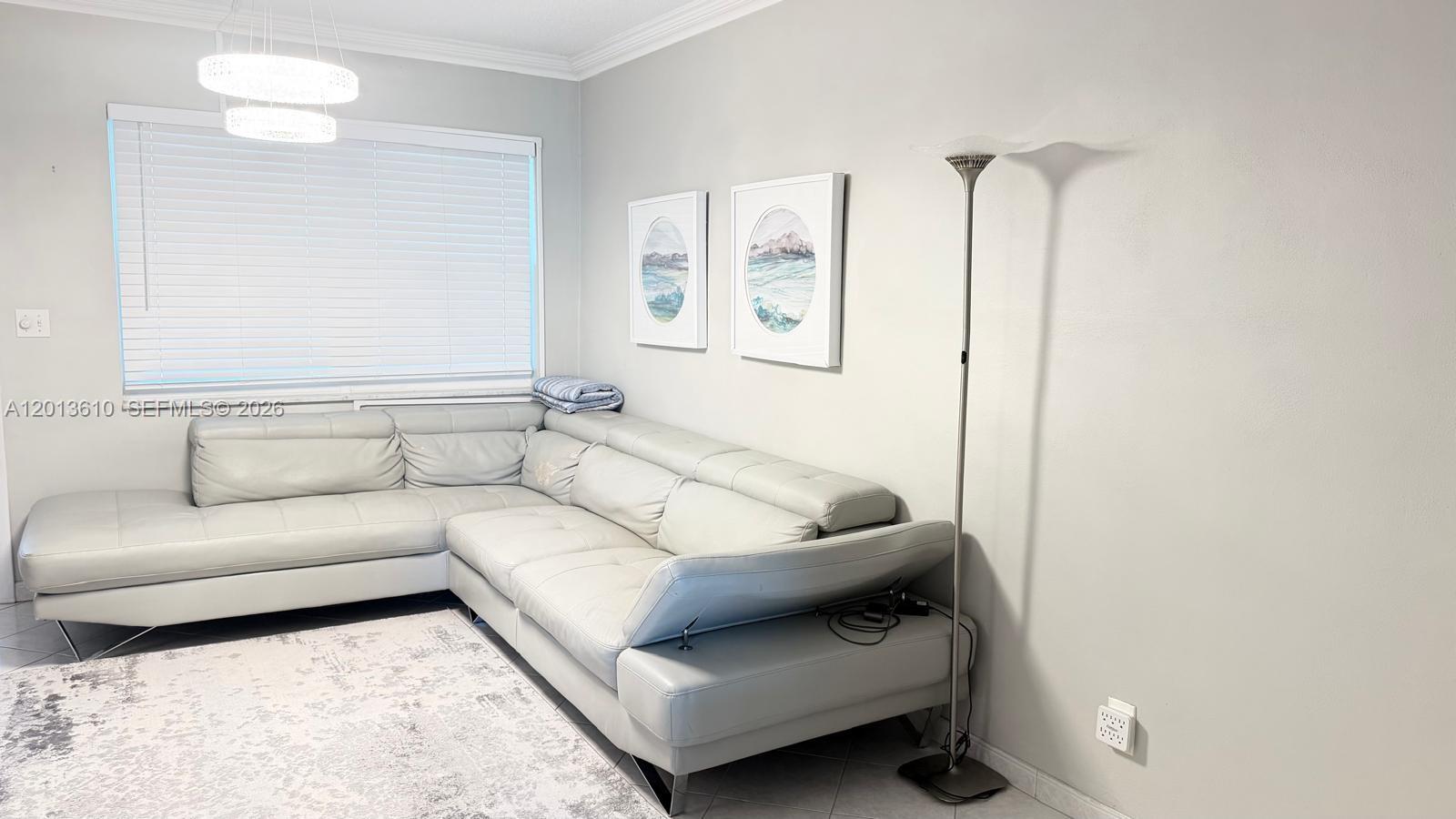 A living room features a light gray sectional sofa, a floor lamp, and two framed prints — 580 Egret Dr # 211, Hallandale Beach FL 33009, HALLANDALE BEACH, FL