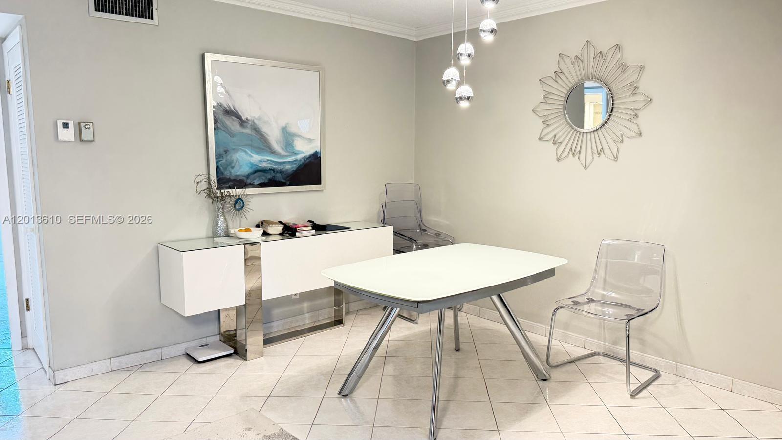 A dining area features a white table, clear acrylic chairs, a sideboard, and wall art — 580 Egret Dr # 211, Hallandale Beach FL 33009, HALLANDALE BEACH, FL