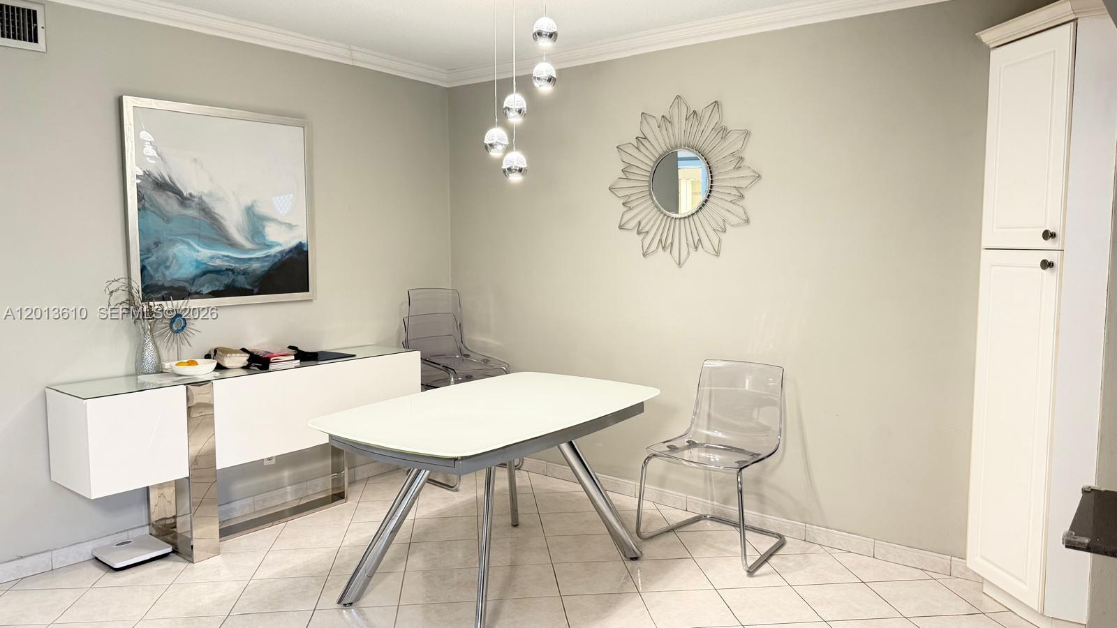 A dining room features a white table, clear chairs, a sideboard, and a sunburst mirror — 580 Egret Dr # 211, Hallandale Beach FL 33009, HALLANDALE BEACH, FL