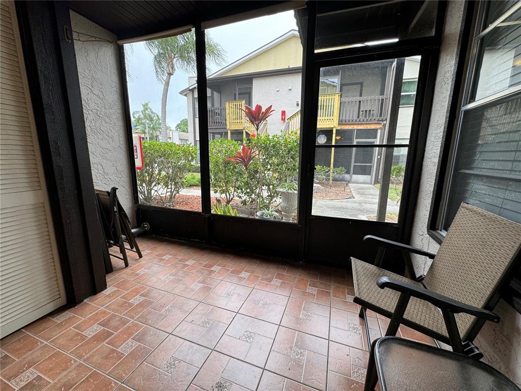 A screened-in porch with tiled flooring overlooks a courtyard and neighboring apartment buildings — 3545 59TH AVENUE W UNIT 3545, BRADENTON, FL