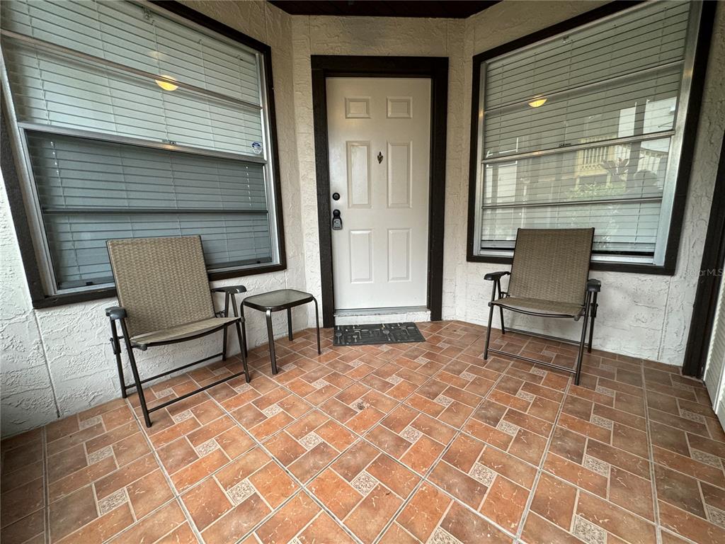 A tiled front porch features two chairs, a small table, and a white entry door — 3545 59TH AVENUE W UNIT 3545, BRADENTON, FL