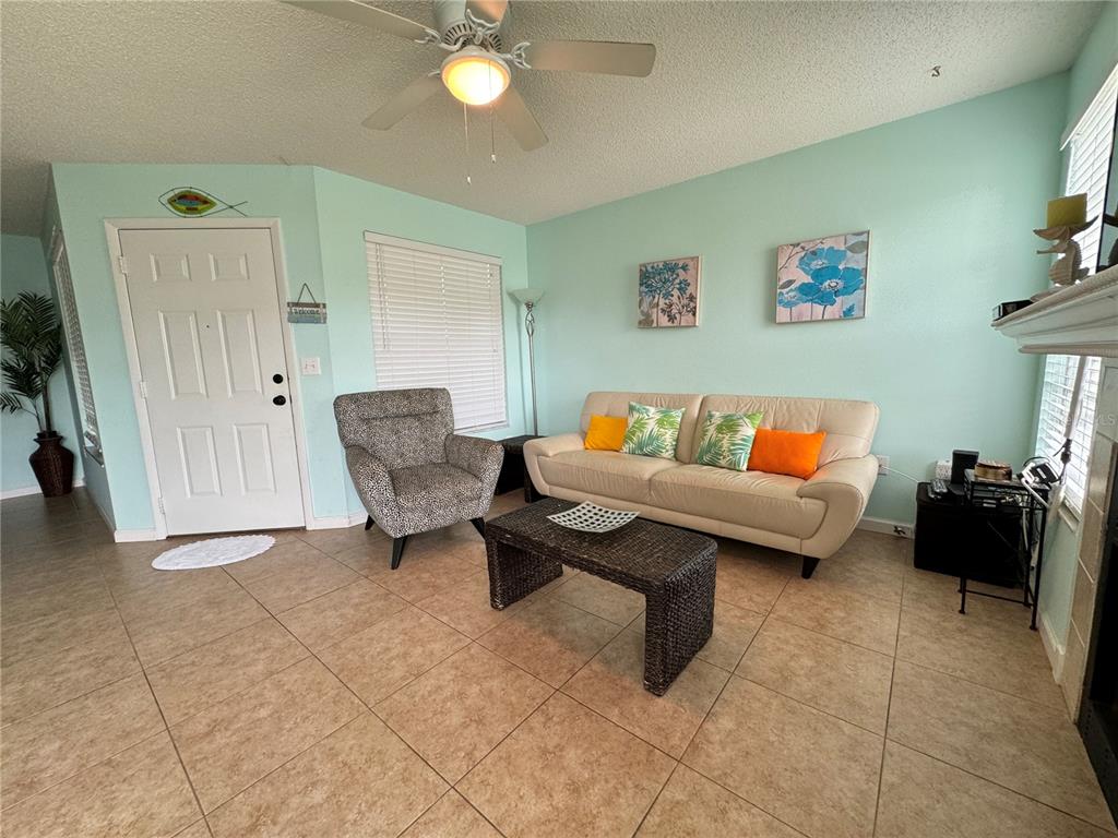 A living room features tile flooring, a beige sofa, an armchair, and a ceiling fan — 3545 59TH AVENUE W UNIT 3545, BRADENTON, FL