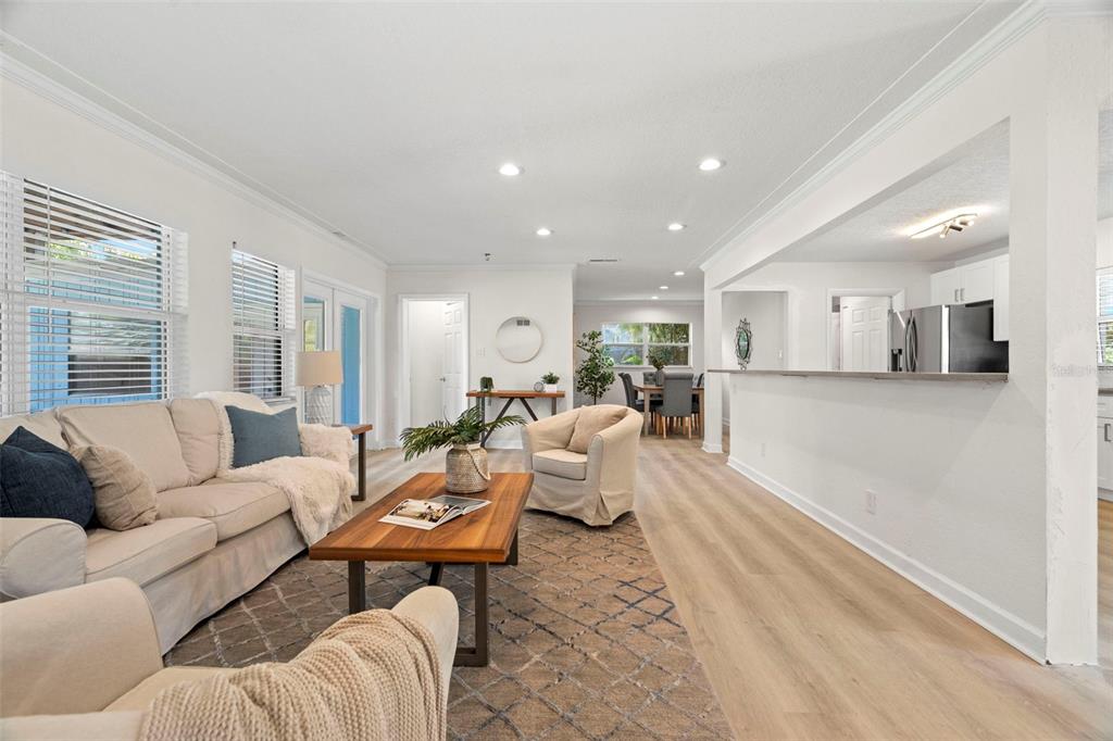 A living room with light wood floors, a beige sofa, and an open kitchen pass-through — 5813 18TH AVENUE S, GULFPORT, FL