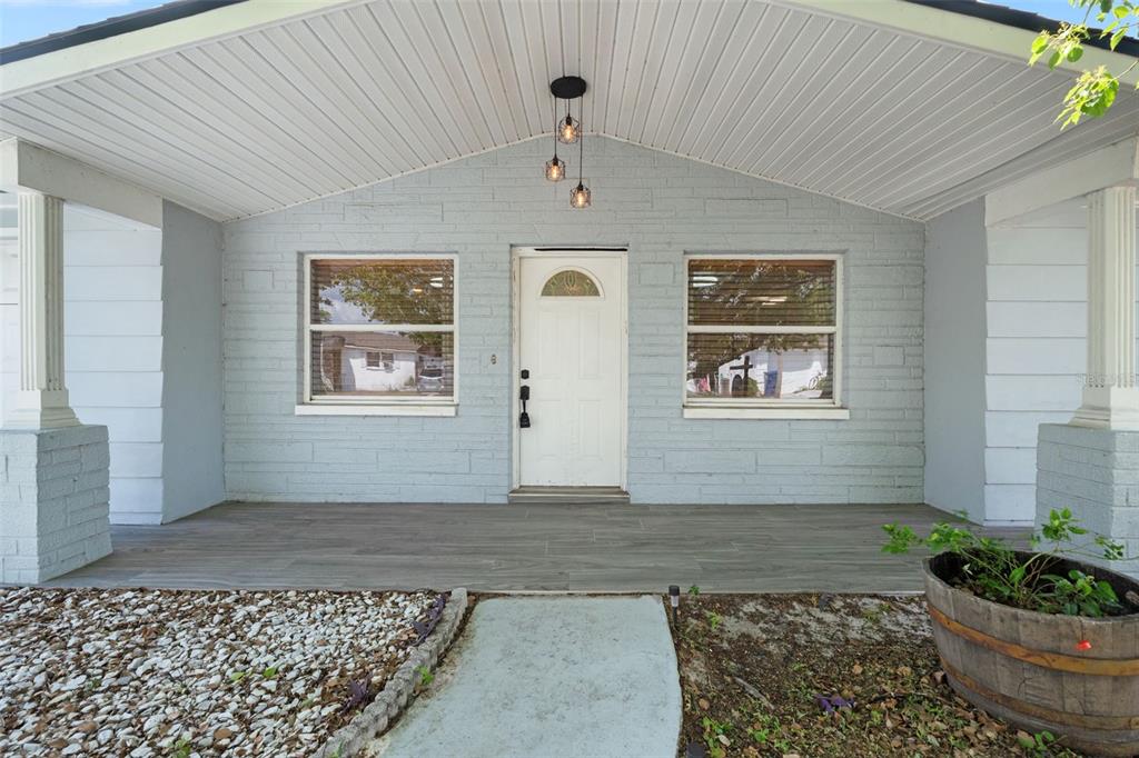 A light blue brick house exterior features a covered porch, white door, and two windows — 1415 BRIXTON LANE, HOLIDAY, FL