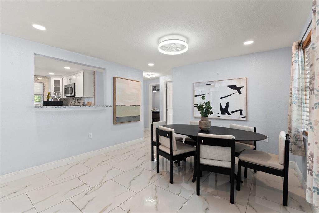 A dining room with a black oval table, chairs, and white marble-look tile flooring — 1415 BRIXTON LANE, HOLIDAY, FL