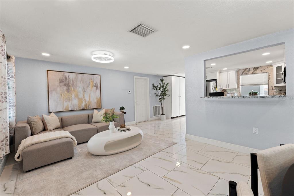 A living room with light blue walls, white tile flooring, and a modern sectional sofa — 1415 BRIXTON LANE, HOLIDAY, FL