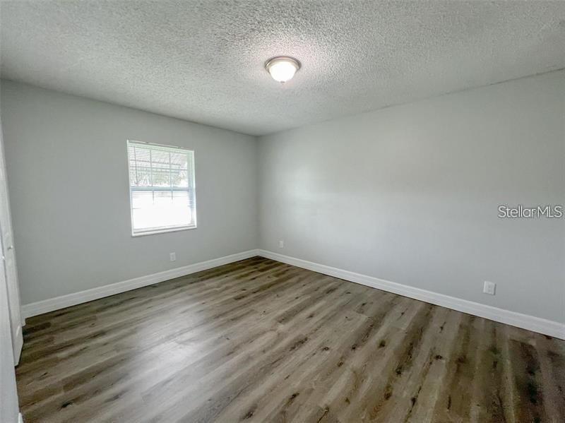 An empty bedroom features light gray walls, wood-look flooring, and a single window — 3008 SAINT PAUL DRIVE UNIT 3012, WINTER HAVEN, FL