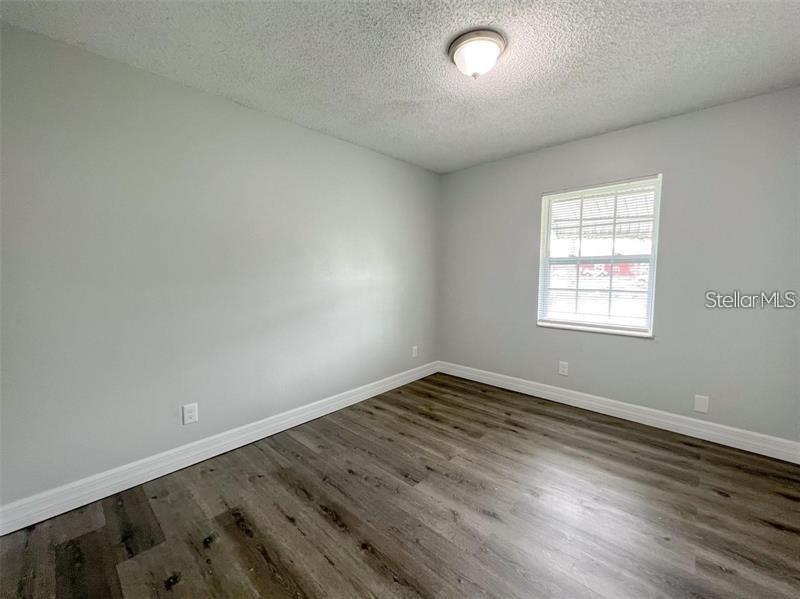 An empty bedroom features light gray walls, white trim, and wood-look vinyl plank flooring — 3008 SAINT PAUL DRIVE UNIT 3012, WINTER HAVEN, FL