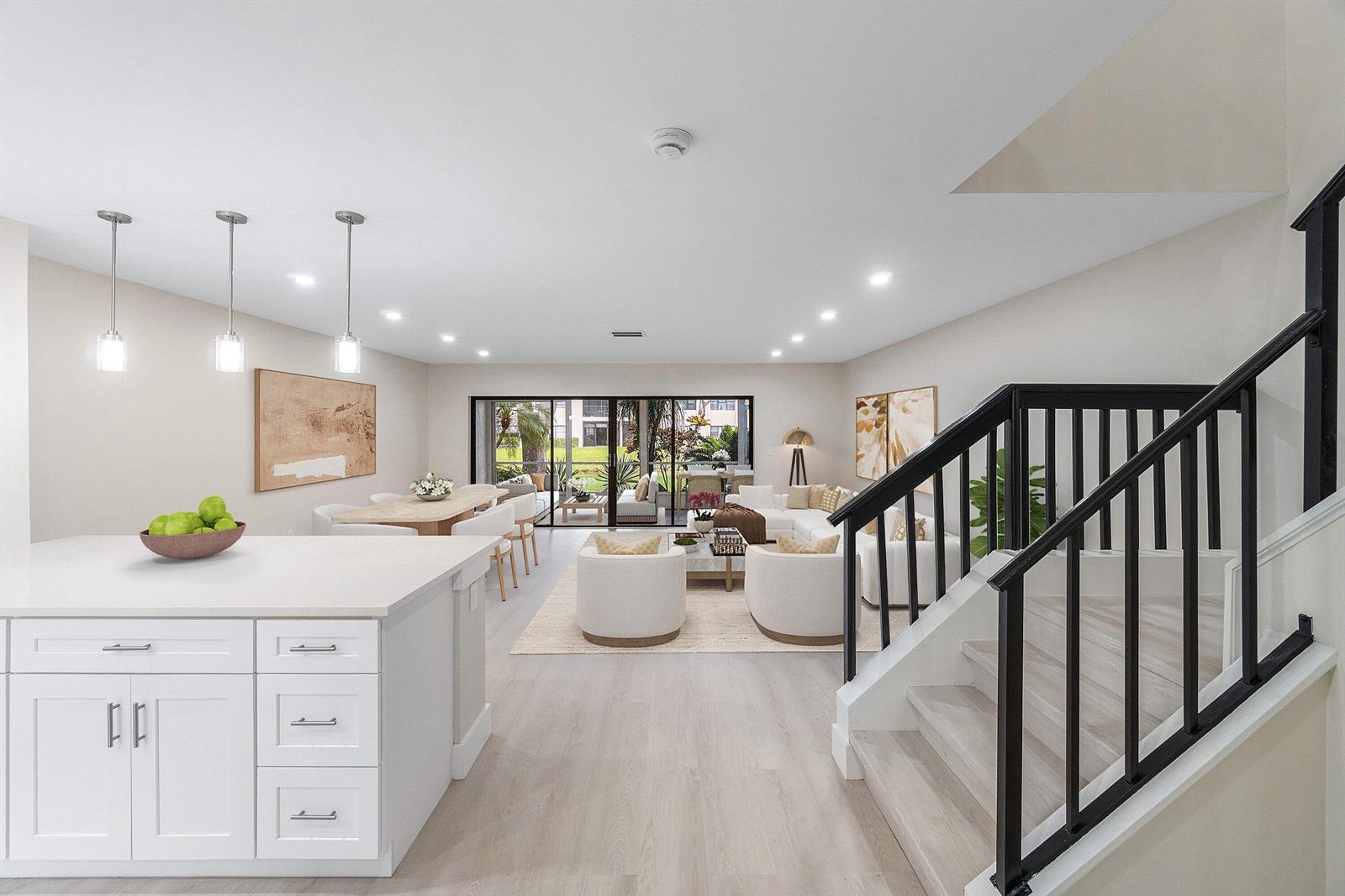 This open-concept living and dining area features a white sectional, marble coffee table, and staircase — 16 Stratford Drive E # C, Boynton Beach FL 33436, BOYNTON BEACH, FL