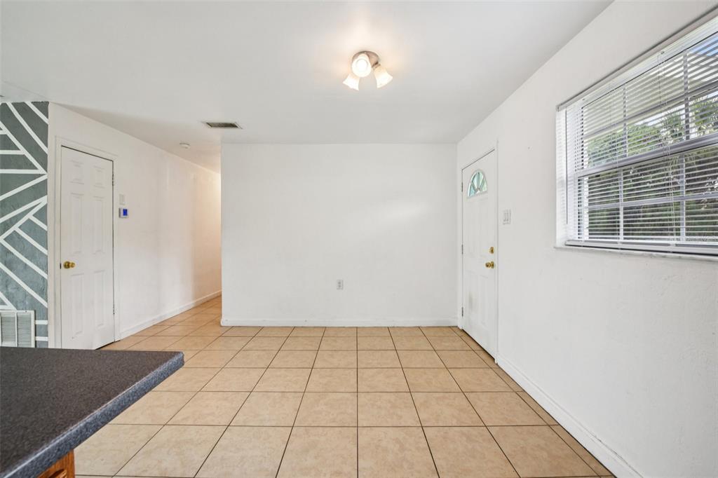 An interior room with white walls, beige tile flooring, a window, and two white doors — 911 SHADY PARK TERRACE, DAYTONA BEACH, FL
