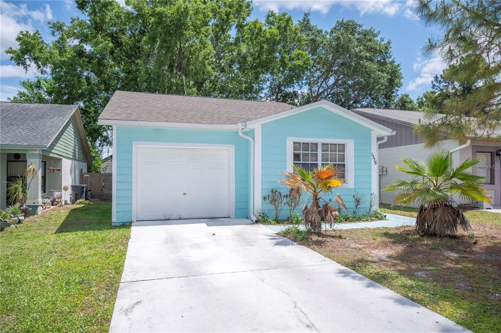 A light blue single-story house features a white garage door and a concrete driveway — 1378 BRAMBLEWOOD DRIVE, LAKELAND, FL
