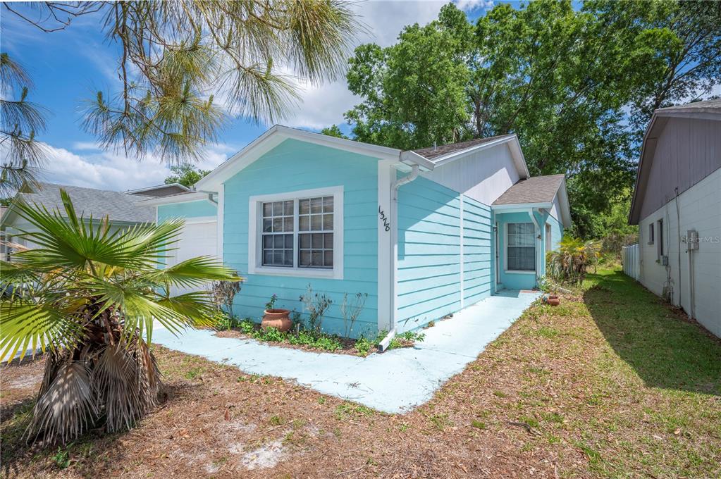 A light blue house with horizontal siding and a painted concrete walkway in the front yard — 1378 BRAMBLEWOOD DRIVE, LAKELAND, FL