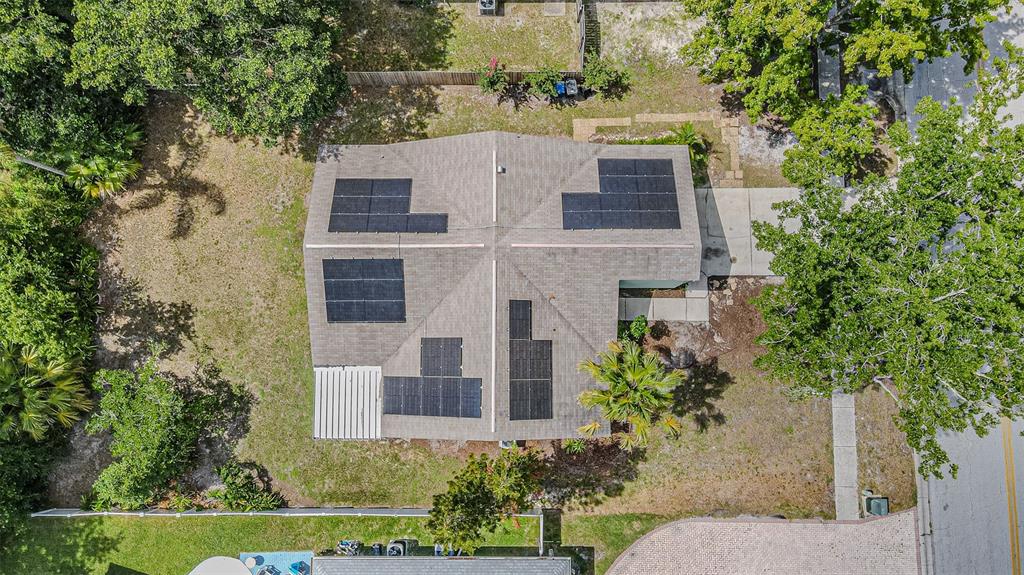 An aerial view shows a house roof with solar panels and surrounding trees and landscaping — 18425 SWAN LAKE DRIVE, LUTZ, FL