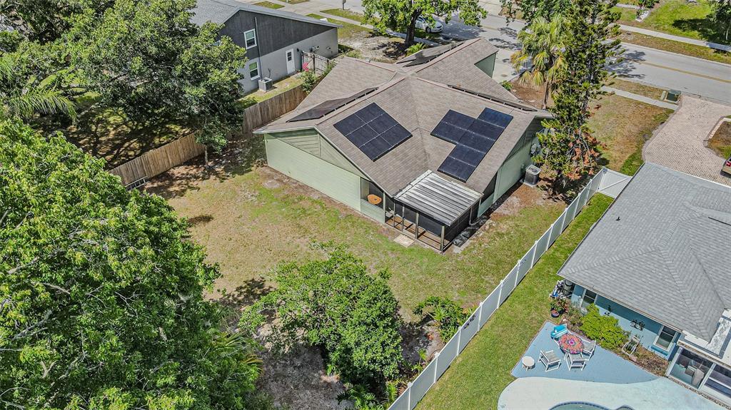 An aerial view shows a house with solar panels on the roof and a backyard — 18425 SWAN LAKE DRIVE, LUTZ, FL