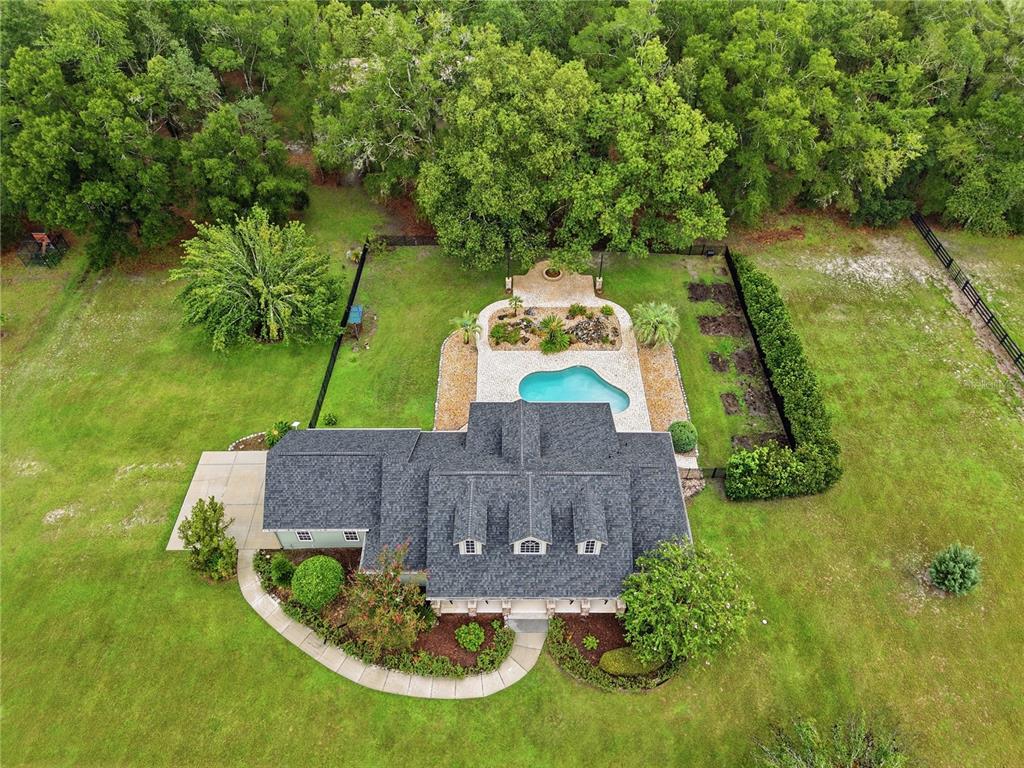An aerial view shows a house with a dark shingled roof, pool, and landscaped backyard — 21158 NW COUNTY ROAD 2054, ALACHUA, FL